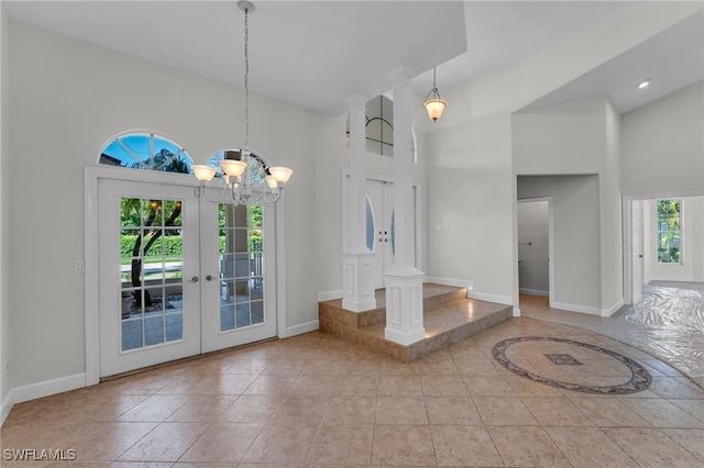 foyer entrance with french doors, high vaulted ceiling, light tile patterned floors, and an inviting chandelier