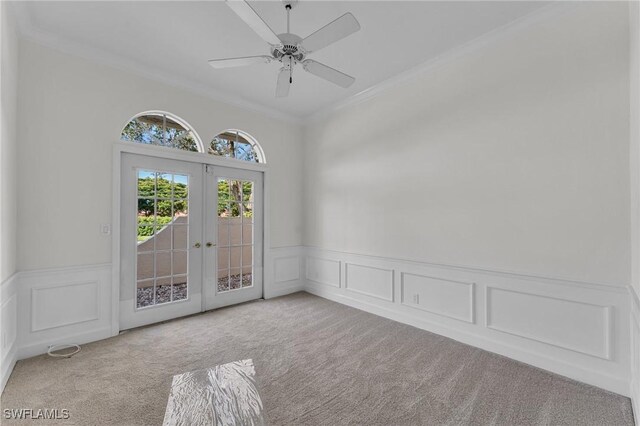 empty room featuring ceiling fan, light colored carpet, ornamental molding, and french doors