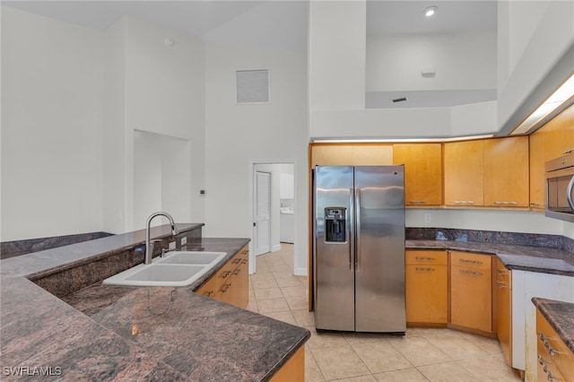 kitchen featuring sink, light tile patterned floors, stainless steel appliances, and a high ceiling