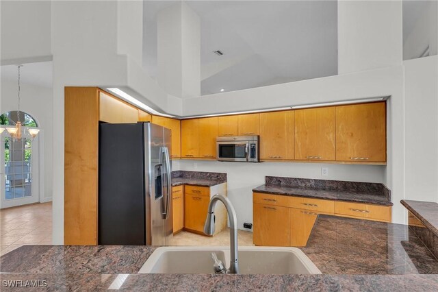 kitchen with stainless steel appliances, sink, decorative light fixtures, high vaulted ceiling, and a chandelier