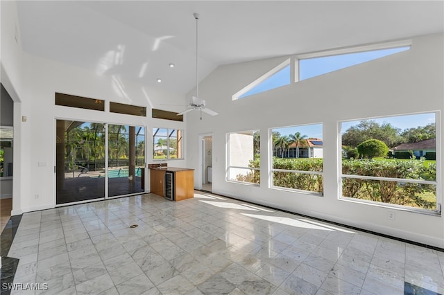 unfurnished living room with ceiling fan and high vaulted ceiling