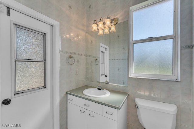 bathroom with vanity, toilet, and tile walls