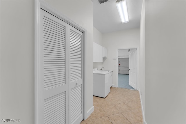 washroom with light tile patterned floors, cabinets, and washer / dryer