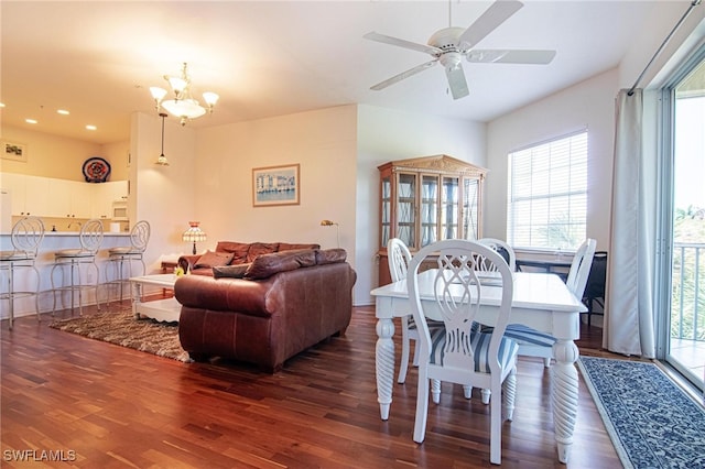 dining room with ceiling fan with notable chandelier and dark hardwood / wood-style flooring