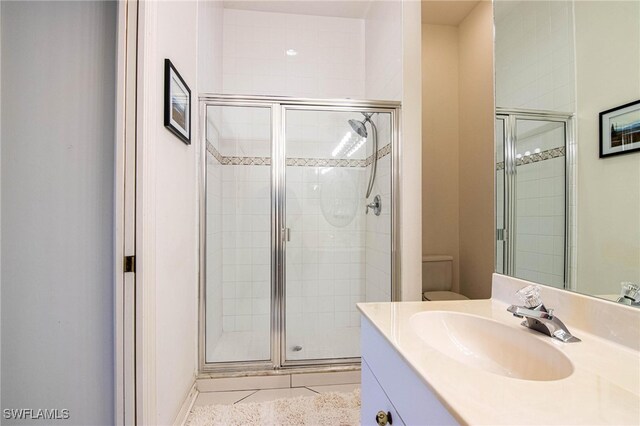 bathroom featuring tile patterned flooring, vanity, toilet, and a shower with shower door