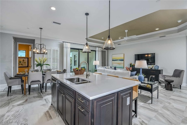 kitchen featuring crown molding, dark brown cabinets, pendant lighting, sink, and an island with sink