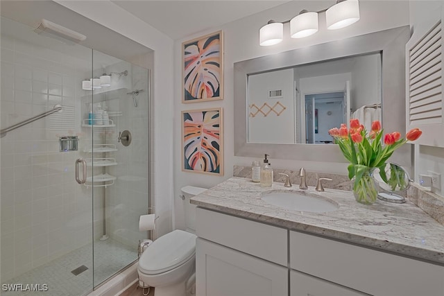 bathroom with vanity, toilet, and a shower with shower door