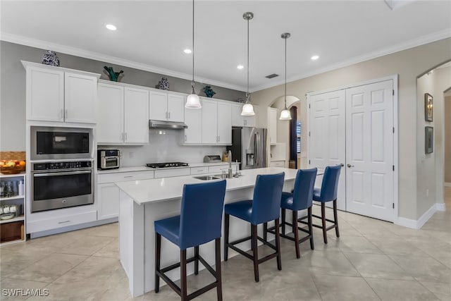 kitchen featuring crown molding, appliances with stainless steel finishes, pendant lighting, sink, and an island with sink