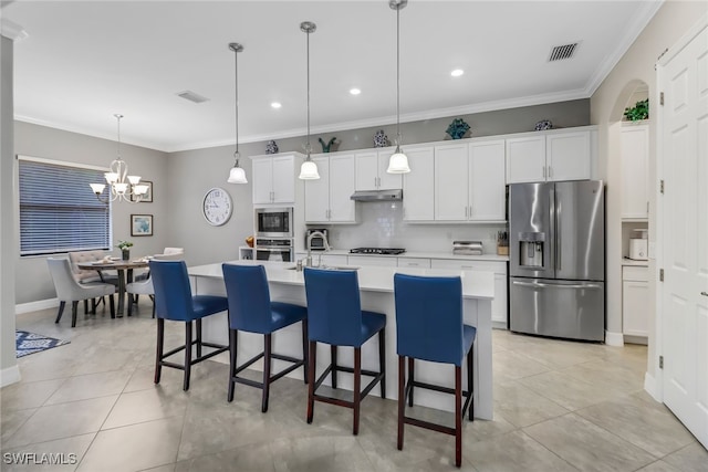 kitchen with white cabinetry, appliances with stainless steel finishes, decorative light fixtures, an inviting chandelier, and an island with sink