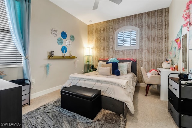 bedroom with wooden walls, ceiling fan, and light carpet