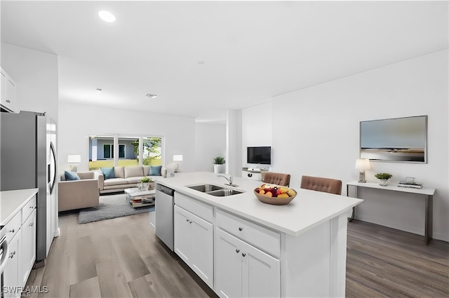 kitchen featuring light wood-type flooring, appliances with stainless steel finishes, sink, white cabinets, and a kitchen island with sink