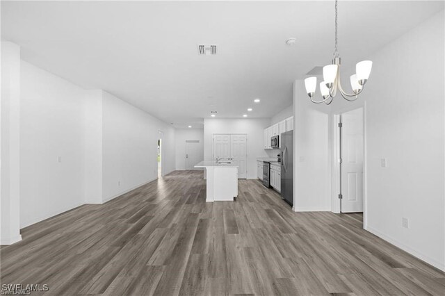 kitchen with white cabinetry, appliances with stainless steel finishes, hanging light fixtures, a kitchen island, and dark hardwood / wood-style flooring