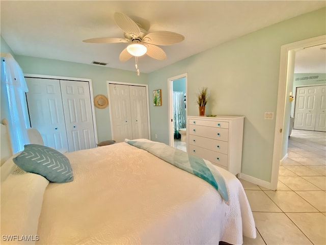 bedroom with ceiling fan, light tile patterned floors, and two closets