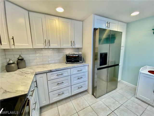 kitchen featuring backsplash, stainless steel refrigerator with ice dispenser, black stove, and white cabinets