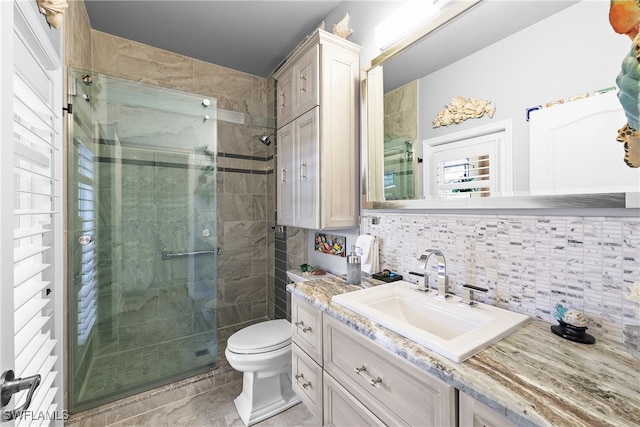 bathroom with decorative backsplash, vanity, a shower with door, tile walls, and toilet