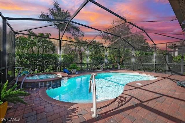 pool at dusk with an in ground hot tub, a patio, and a lanai