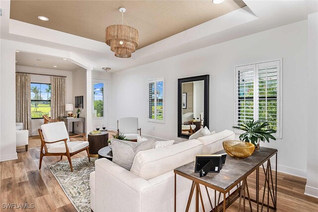 living room featuring hardwood / wood-style floors, a healthy amount of sunlight, and a raised ceiling