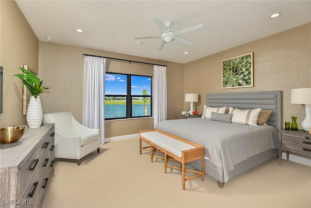 carpeted bedroom featuring a water view and ceiling fan