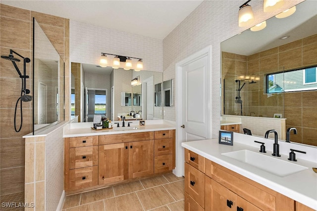 bathroom featuring tile patterned flooring, vanity, a healthy amount of sunlight, and a tile shower