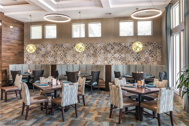 dining space featuring wood walls and coffered ceiling