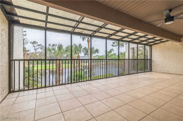 unfurnished sunroom featuring a water view, ceiling fan, and beam ceiling