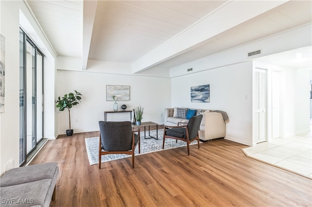 living room with beam ceiling, wooden ceiling, a healthy amount of sunlight, and light hardwood / wood-style flooring