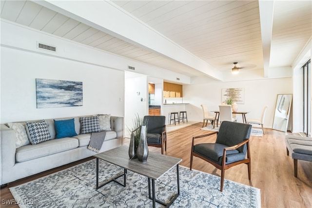 living room with light hardwood / wood-style floors and beamed ceiling