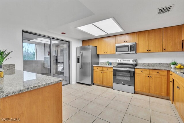 16448 Timberlakes Dr Unit 202, Fort Myers, FL 33908 - kitchen featuring appliances with stainless steel finishes, light tile patterned floors, light stone counters, and brown cabinets