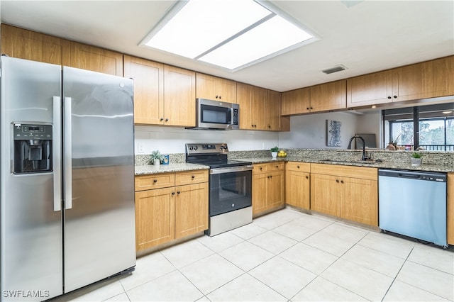 kitchen featuring appliances with stainless steel finishes, sink, light stone counters, and light tile patterned floors