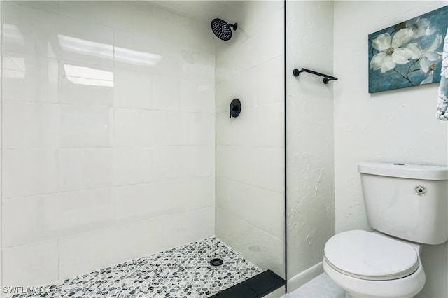 bathroom with tiled shower and toilet