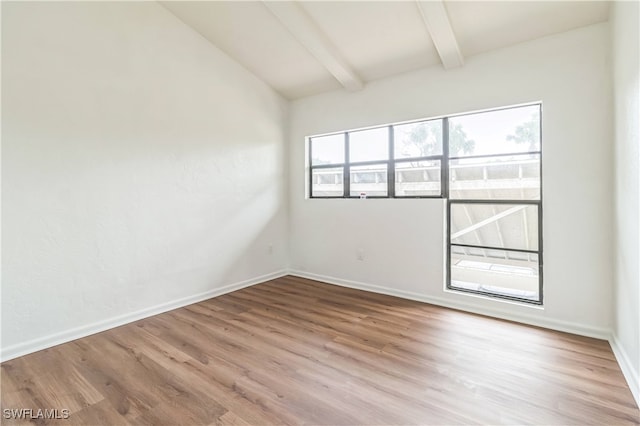 spare room with lofted ceiling with beams and light hardwood / wood-style floors