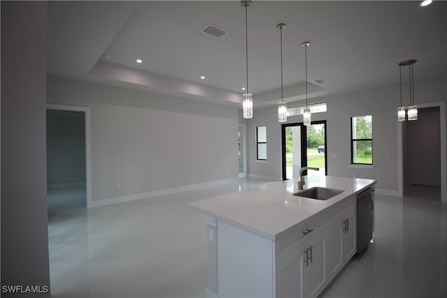 kitchen featuring a center island with sink, sink, light stone countertops, white cabinetry, and decorative light fixtures