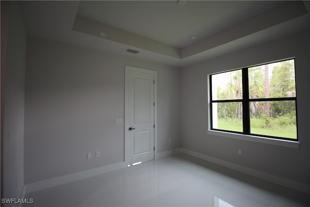 unfurnished room featuring tile patterned floors and a tray ceiling