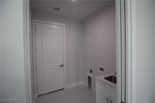 laundry room with hookup for an electric dryer, washer hookup, light tile patterned floors, cabinets, and sink