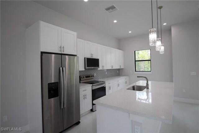 kitchen featuring light stone counters, a center island with sink, stainless steel appliances, white cabinetry, and sink