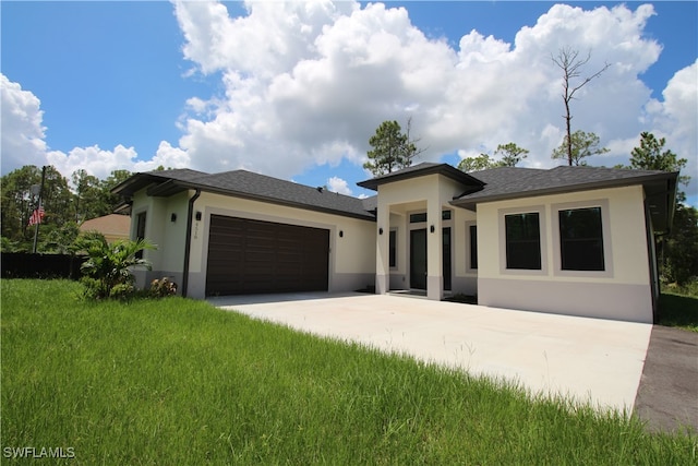 prairie-style home featuring a garage and a front lawn