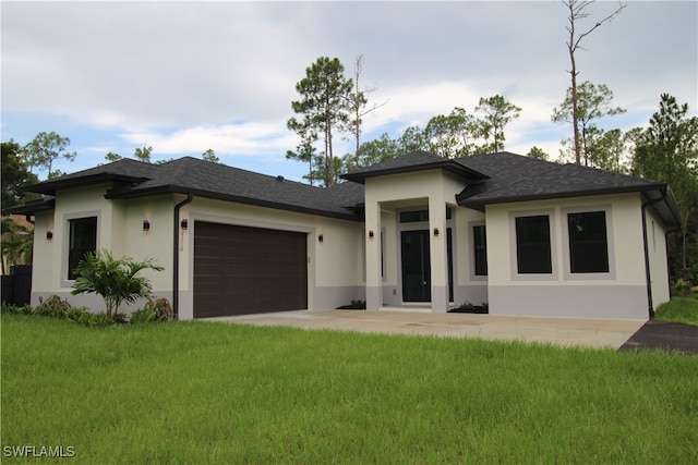 prairie-style home featuring a garage and a front lawn