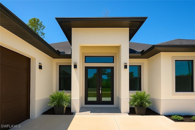 entrance to property featuring a shingled roof, french doors, and stucco siding