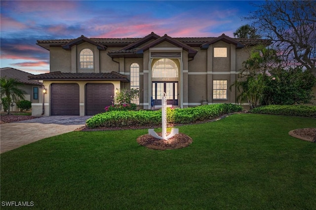 mediterranean / spanish home featuring a yard, french doors, and a garage