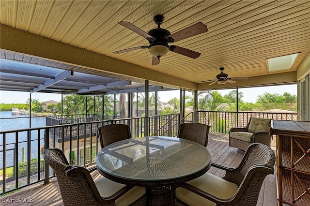 sunroom / solarium with ceiling fan and a water view