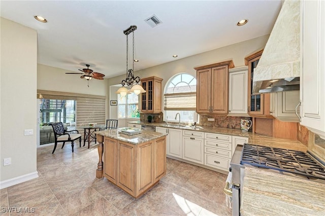 kitchen featuring ceiling fan, a center island, sink, premium range hood, and appliances with stainless steel finishes