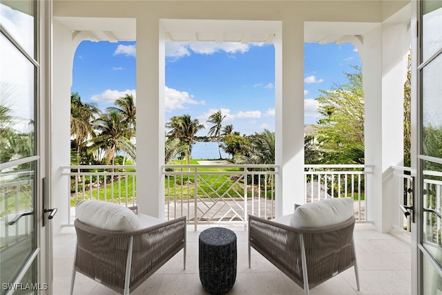 sunroom featuring french doors and a water view