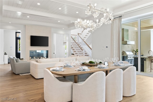 dining area featuring beam ceiling, wooden ceiling, a chandelier, and light wood-type flooring