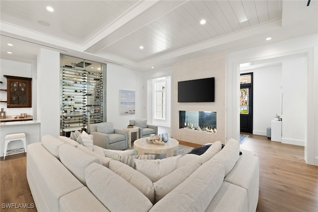 living room with hardwood / wood-style floors, a large fireplace, wooden ceiling, and beam ceiling