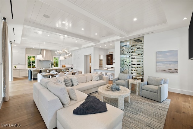 living room with beamed ceiling, light hardwood / wood-style floors, wooden ceiling, and a chandelier