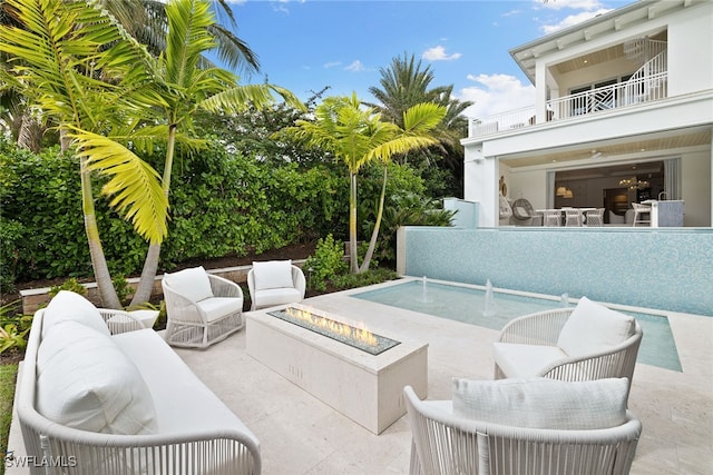 view of patio featuring a balcony and an outdoor living space with a fire pit