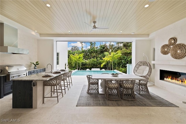 12 Sabre Ln, Naples, FL 34102 - view of patio / terrace featuring exterior kitchen, a glass covered fireplace, ceiling fan, outdoor dining area, and an outdoor pool