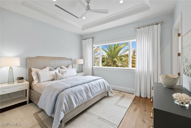 bedroom featuring a raised ceiling, ceiling fan, light hardwood / wood-style floors, and ornamental molding