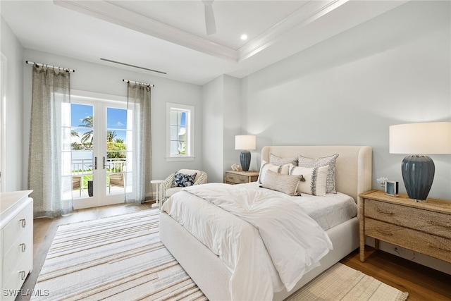 bedroom featuring access to outside, french doors, light hardwood / wood-style flooring, ceiling fan, and a tray ceiling