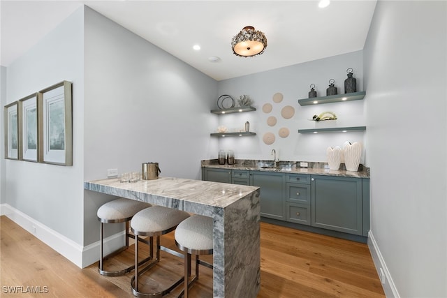 bar featuring light hardwood / wood-style flooring and sink